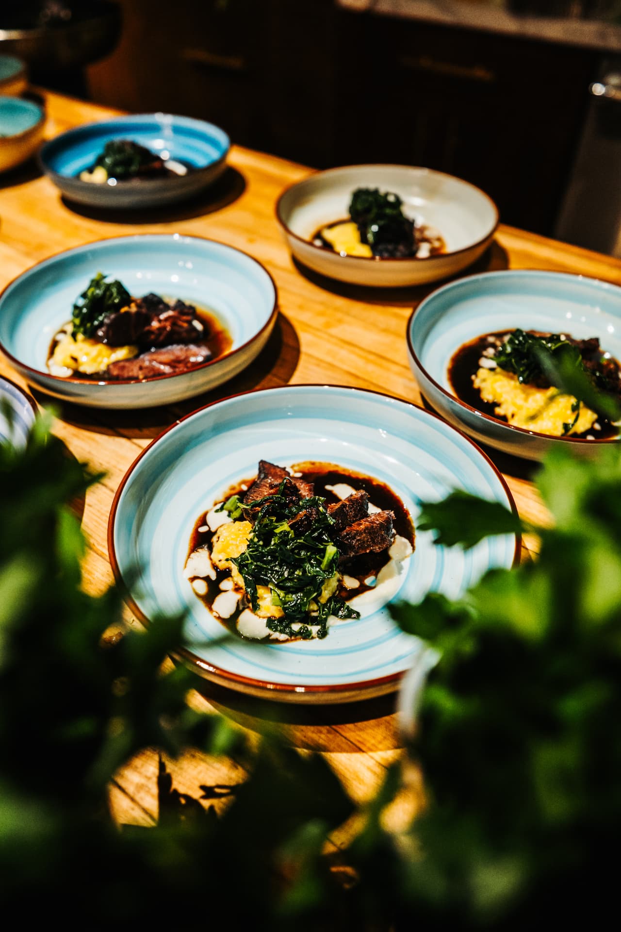 Plated courses lined up on a wooden table at a Dirty Napkins dinner