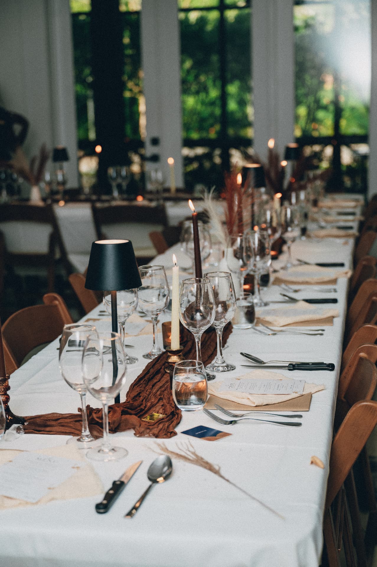 A long supper table set with wine glasses, candles and place settings