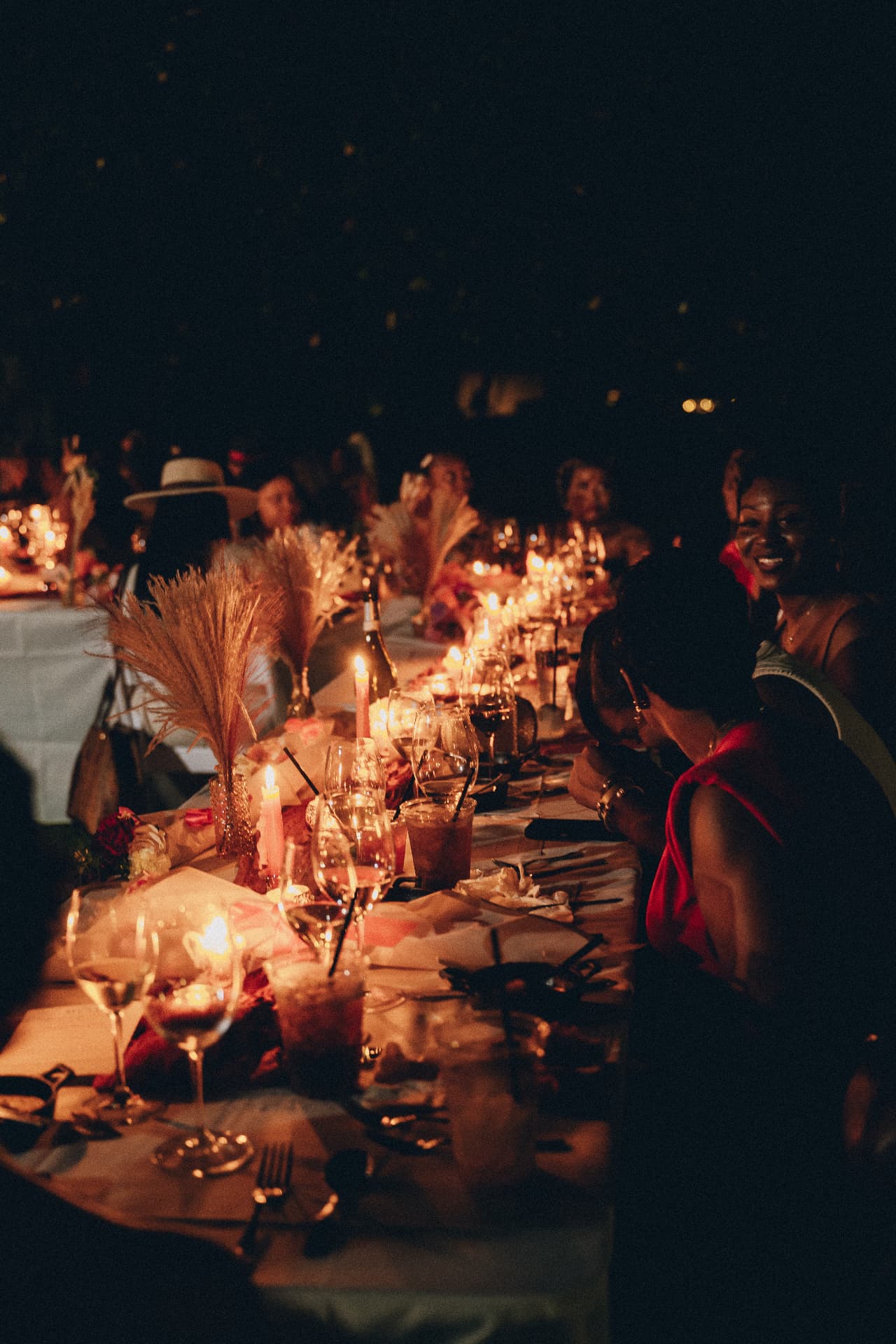 A candlelit Dirty Napkins dinner table at night with pampas grass and wine